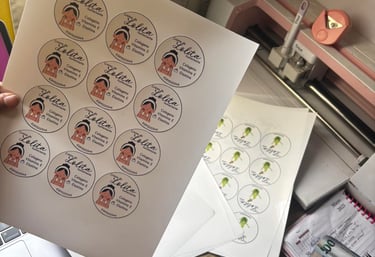 Custom printed cosmetic labels for skincare products displayed on a craft desk with a Cricut machine.