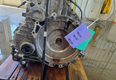 Used car transmission assembly with purple identification tag on a wooden pallet.