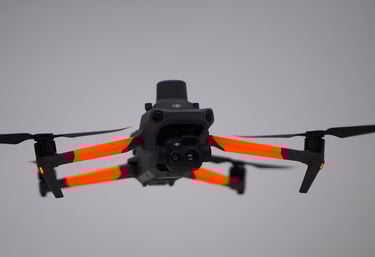 A DJI Mavic 3 Enterprise thermal drone with orange arms hovering in flight against a grey background.