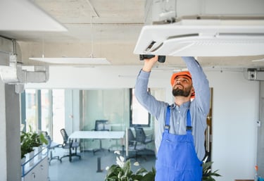 handyman performing maintenance on air conditioning unit in a commercial property in Auckland