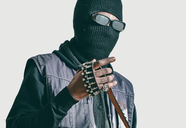 Studio photo of a man in a black jacket and a mask on, holding a belt
