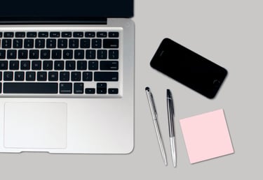 ordenador, movil, bolis y notas sobre la mesa