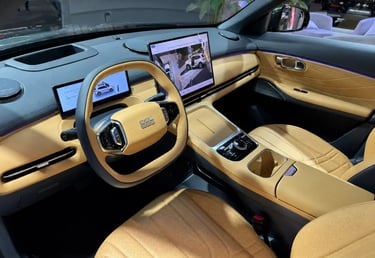 Interior do Geely EX5 com bancos claros, painel digital e central multimídia