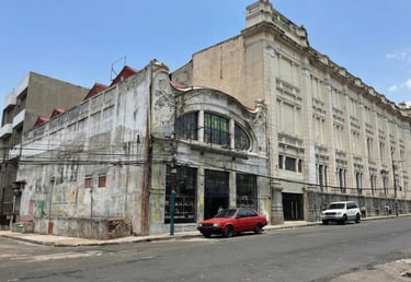 Historic art deco architecture in San Salvador featuring a red car parked on a city street.
