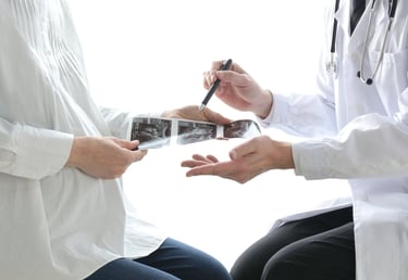 A doctor showing a baby ultrasound scan to a pregnant patient during a prenatal checkup.