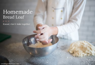 A baker with floured hands preparing dough for a homemade bread loaf in a kitchen.