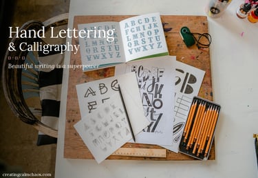 An overhead view of hand lettering and calligraphy practice sheets with graphite drawing pencils.