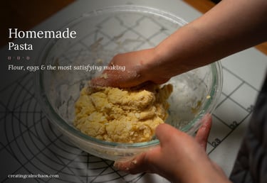 A person kneading fresh homemade pasta dough by hand in a glass bowl.
