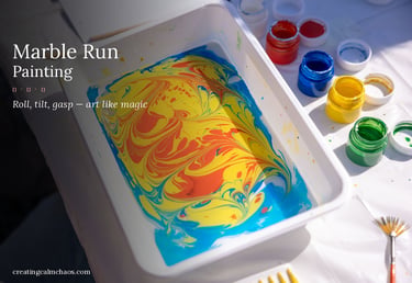 Swirling yellow, blue, and red paint in a marble run painting tray next to colorful art supplies.