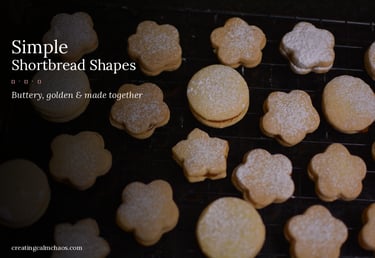 Homemade flower and round shaped shortbread cookies dusted with powdered sugar on a cooling rack.