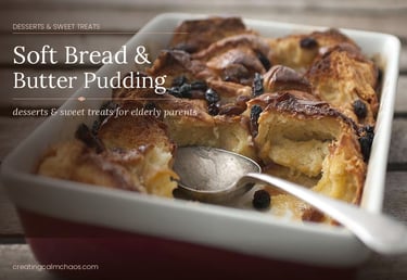 Golden brown soft bread and butter pudding with raisins in a baking dish with a serving spoon.