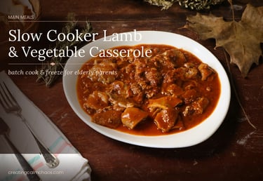 A white plate of slow cooker lamb and vegetable casserole on a rustic wooden table.