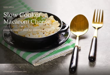 Slow cooker macaroni cheese in a black bowl with a gold spoon and fork on a marble table.