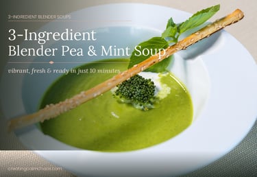 A bowl of creamy green pea and mint soup garnished with a breadstick and fresh herbs.