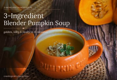 A bowl of 3-ingredient blender pumpkin soup topped with seeds and mint on a wooden table.