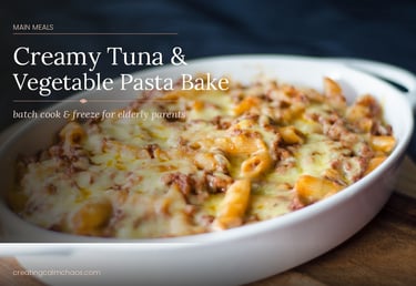 A creamy tuna and vegetable pasta bake topped with melted cheese in a white casserole dish.