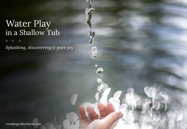 A child's hand reaching for splashing water drops during sensory water play in a shallow tub.
