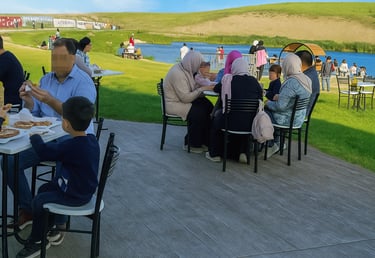 عائلة تتناول البيتزا في مطعم على الهواء الطلق يطل على بحيرة