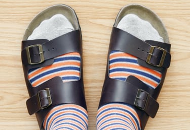 A picture looking down at two feet wearing socks and sandals
