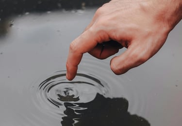 a person's hand is touching a water droplet