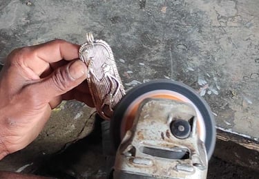 "A tribal artisan carefully filing and refining excess brass from a sculpture after casting in the traditional Dhokra art"