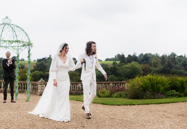 a bride and groom walking down a gravel path