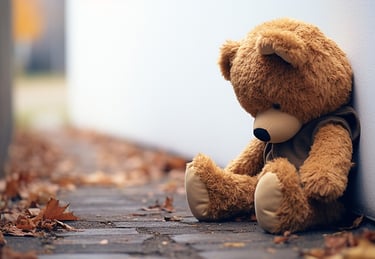 a teddy bear sitting on the ground next to a wall