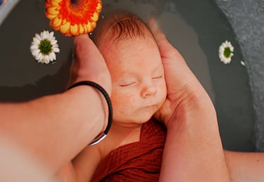 Un bébé portant un bob est tenu dans les bras d'une femme.