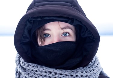 Portrait d'une femme portant une veste noire et un foulard autour du cou dans un décor de neige
