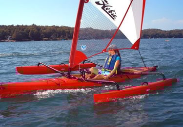 a man is sitting on a red kayak with sail