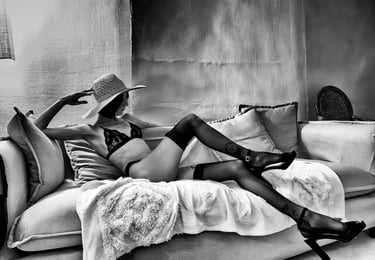 Photo artistique noire et blanc d'une élégante jeune femme en sous vêtements et bas  allongée sur un canapé 