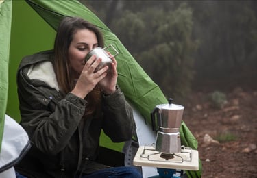 uma mulher sentada em uma tenda com uma xícara de café