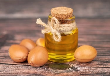 Glass bottle containing Argan oil and surrounded by Argan nuts