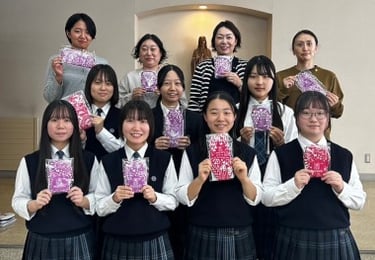 Eleven teachers and school girls holding up Hanaru's sanitary napkins.