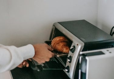 A person using a toaster oven as an energy savings alternative to using a traditional oven.