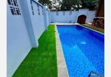Kolam Renang minimalis dengan dekorasi rumput sintetis di area tepi