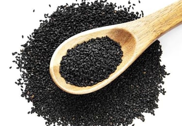 a wooden spoon with black sesame seeds and some of seeds on the ground