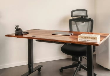 A chair behind a desk with a closed laptop, books, and old-style phone.