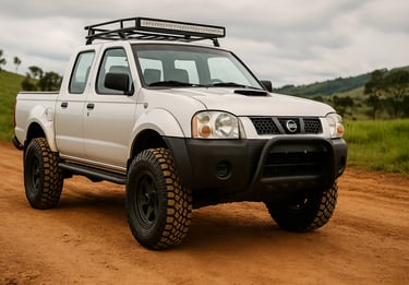 Nissan Frontier 2000 preparada para off-road, com pneus grandes e suspensão elevada em estrada de te