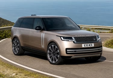 Range Rover de luxo em estrada costeira com vista para o mar.