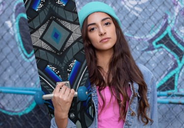 a woman in a pink shirt and jeans jacket holding a skateboard