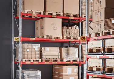 Industrial warehouse storage racks with cardboard boxes on pallets for organized distribution.