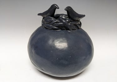 Round black clay pot with birds on top