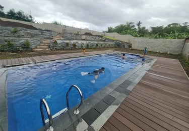 Kolam infinity menghadap taman tropis dengan pepohonan rindang.