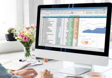a person sitting at a desk with a computer monitor and a cup of coffee