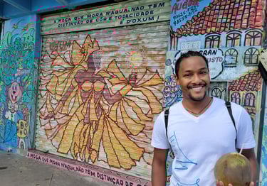 Wil smiling with a coconut in hand in Salvador in front of a drawing of Oshun