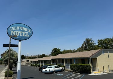 a motel sign that says california motel with the motel in the background and a blue sky