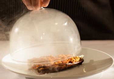glass lid filled with smoke lifted off gormet meal 