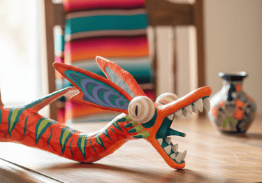 Hand-painted Mexican alebrije dragon folk art sculpture on a wooden dining table.
