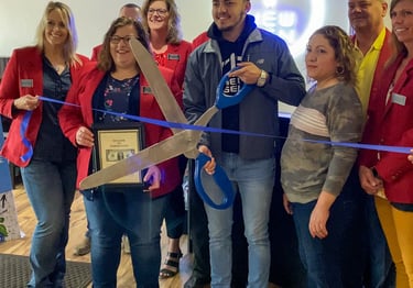 a group of people holding scissors and cutting a ribbon